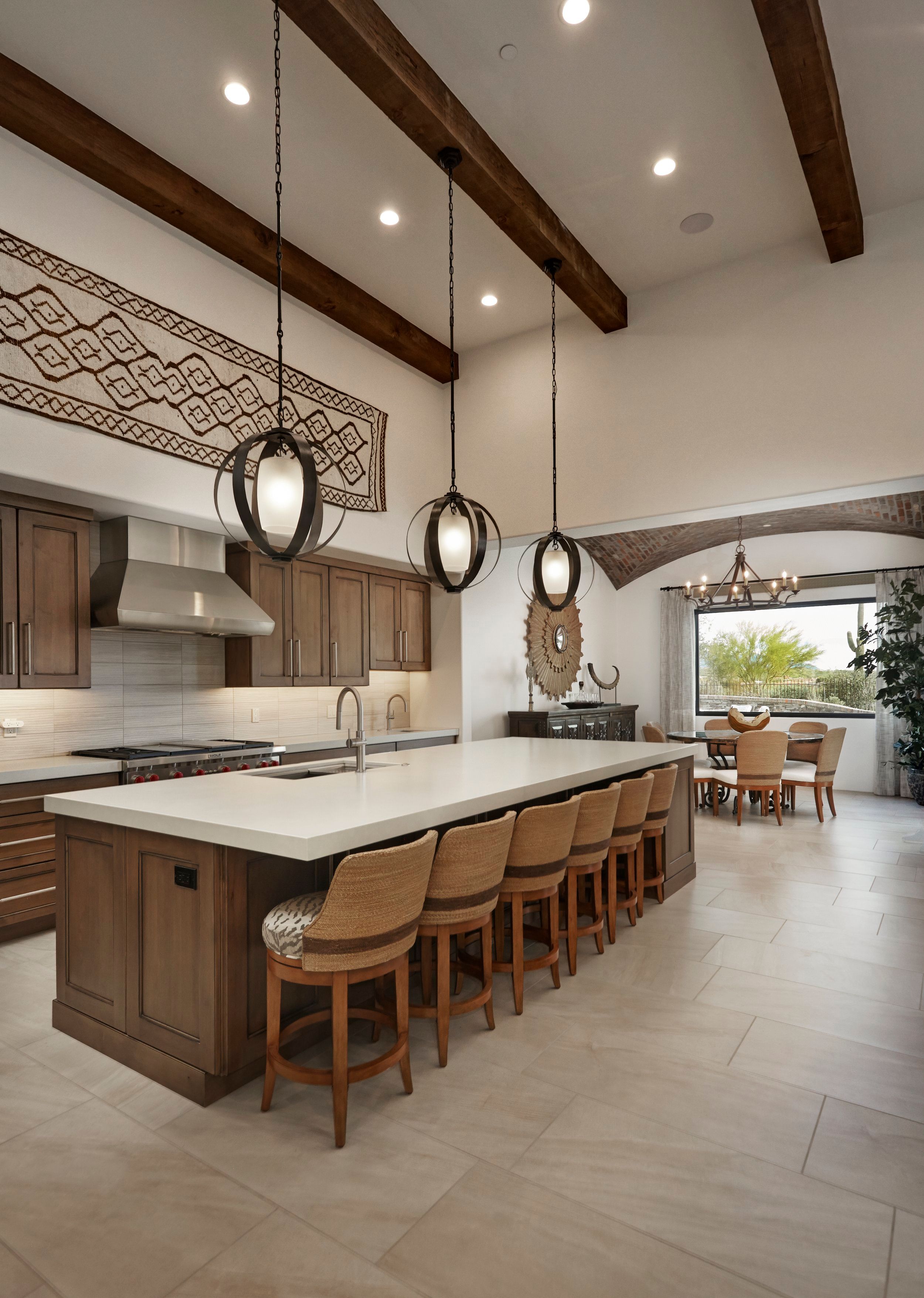 Kitchen with a long stone island, woven pendant lights and a beamed ceiling