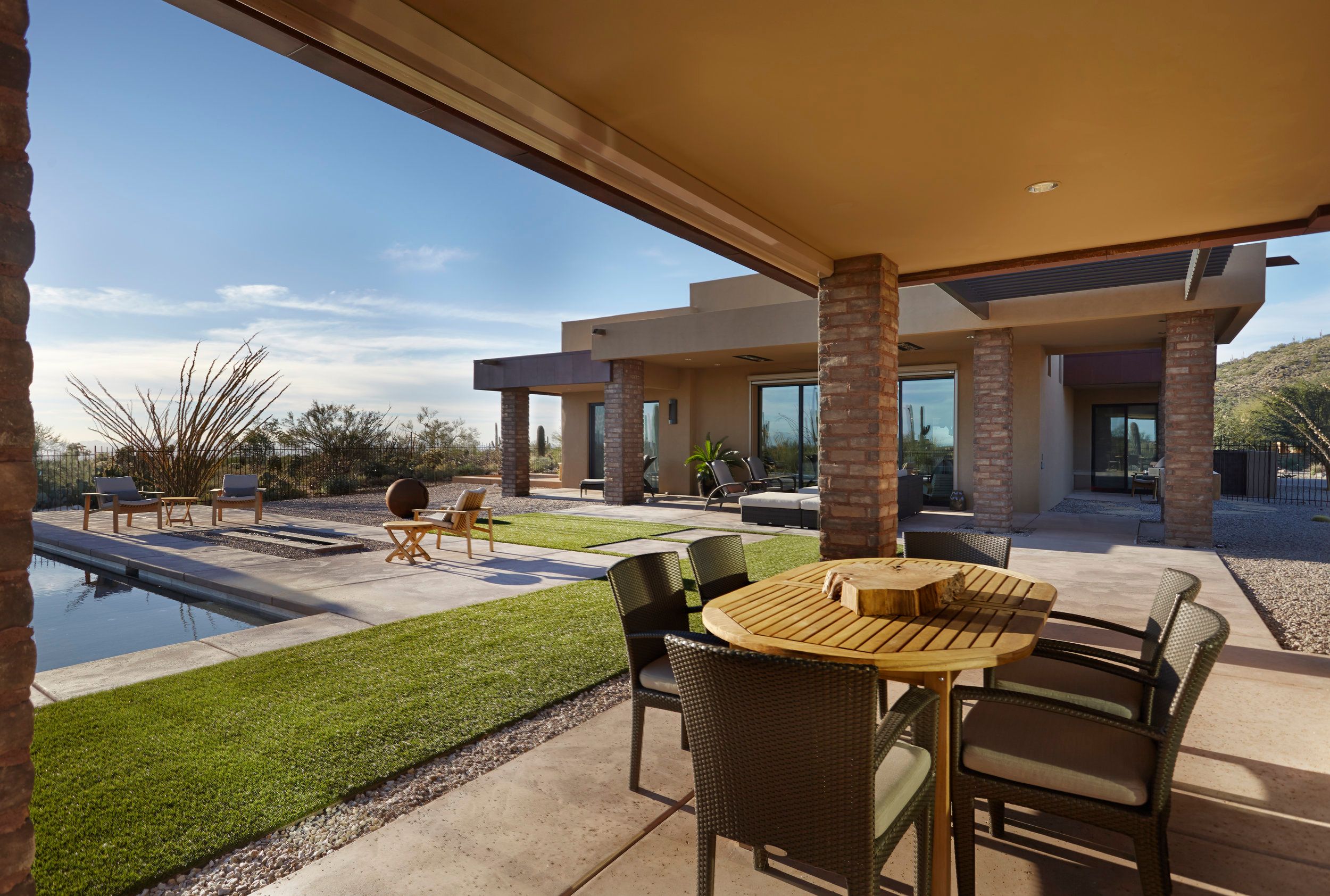 Covered patio with outdoor dining, stone columns and the pool alongside