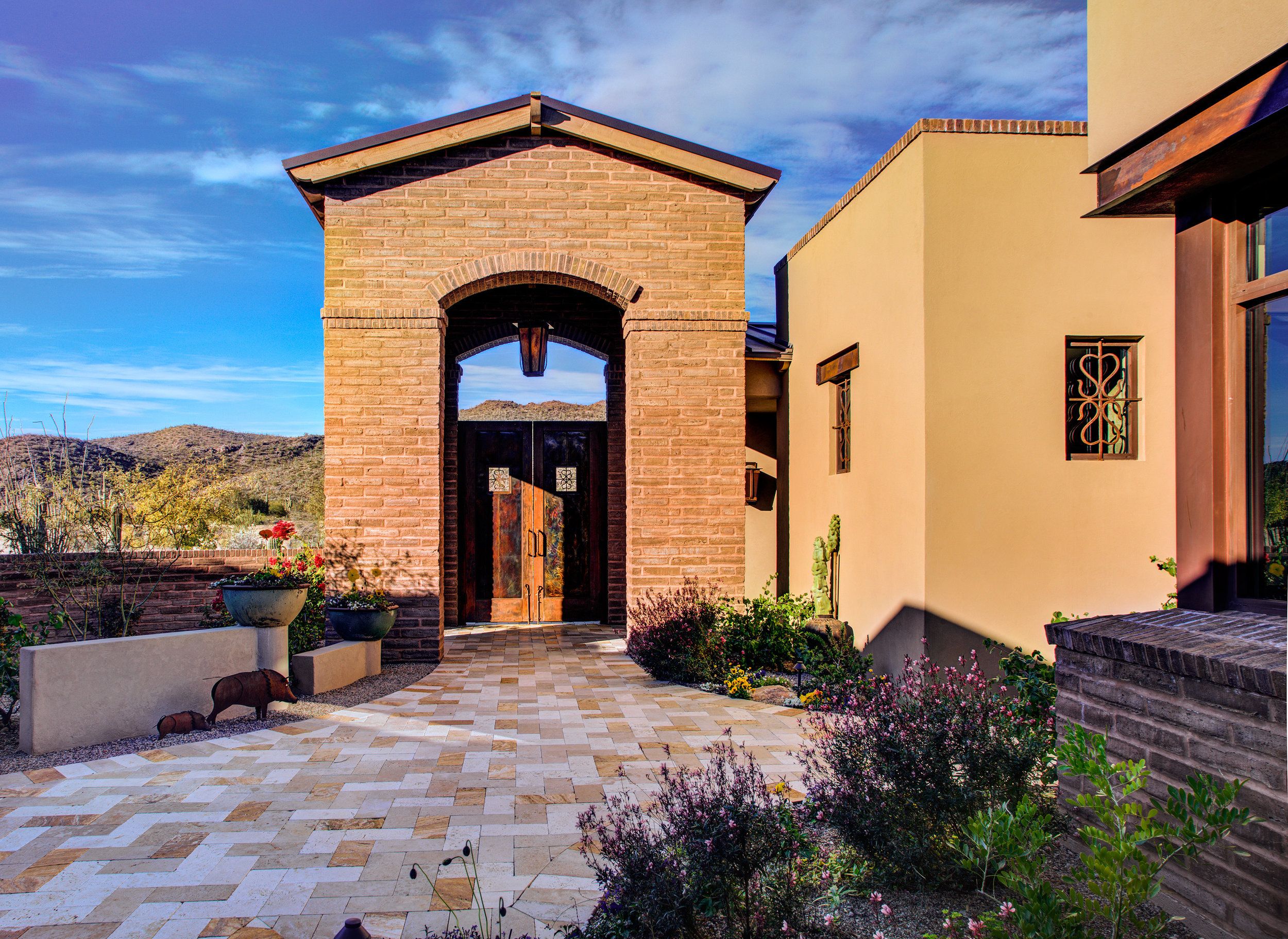 Brick entry tower with a pitched tile roof seen across the courtyard pavers