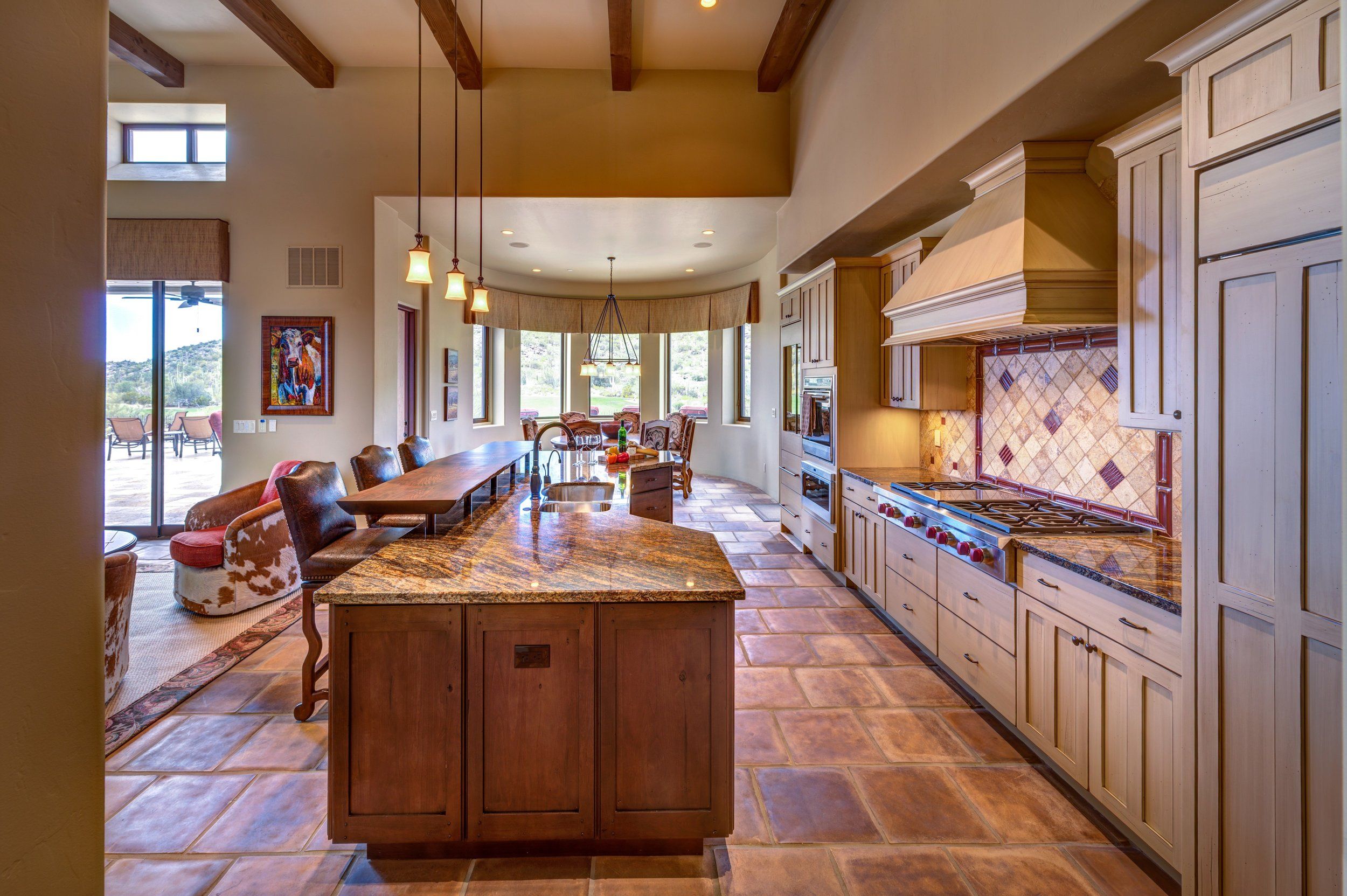 Kitchen with a wood hood, granite island and dining area beyond