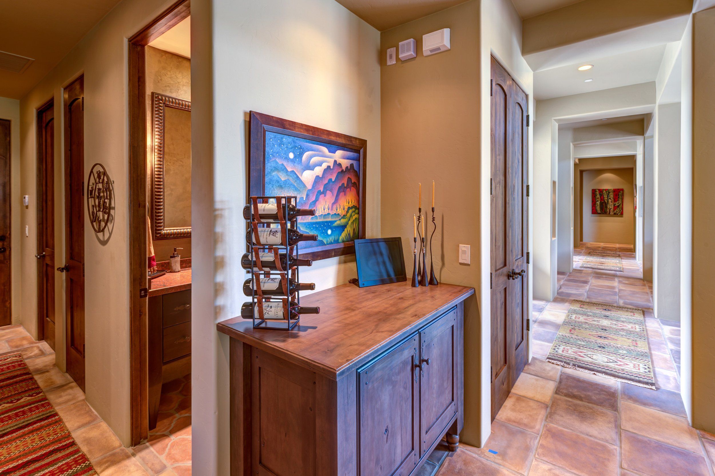 Hallway with a wood console, framed artwork and saltillo tile flooring
