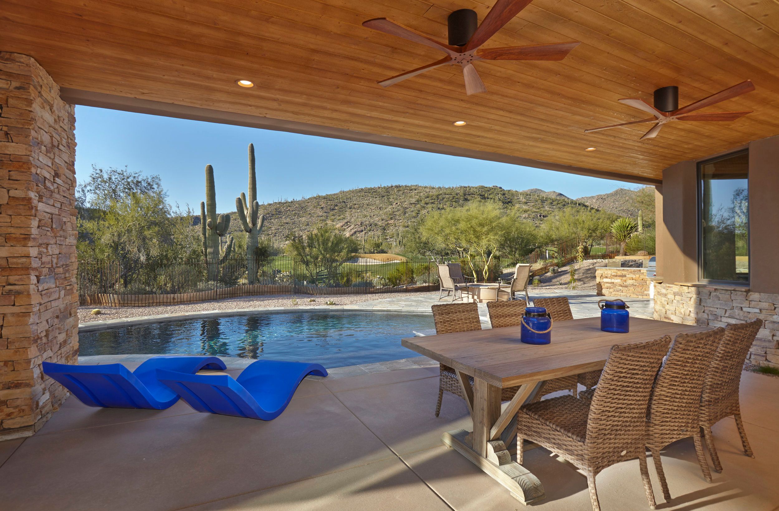 Covered patio with outdoor dining looking across the pool to the desert