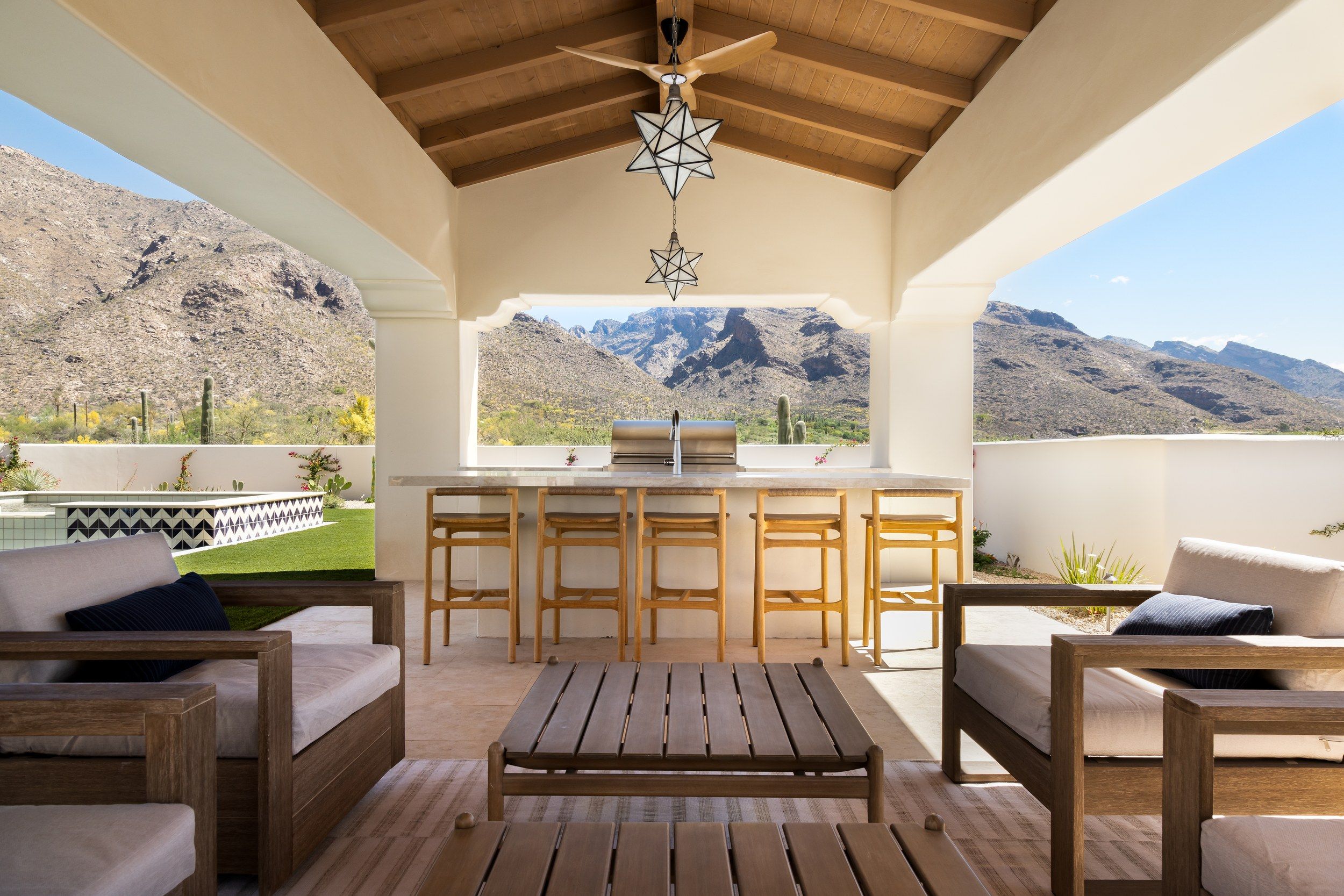 Covered outdoor lounge with bar seating, star pendants and a mountain view