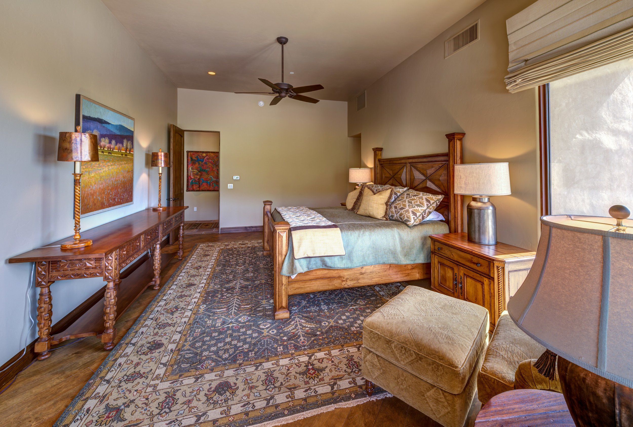 Guest bedroom with a carved bed frame, patterned rug and shuttered window