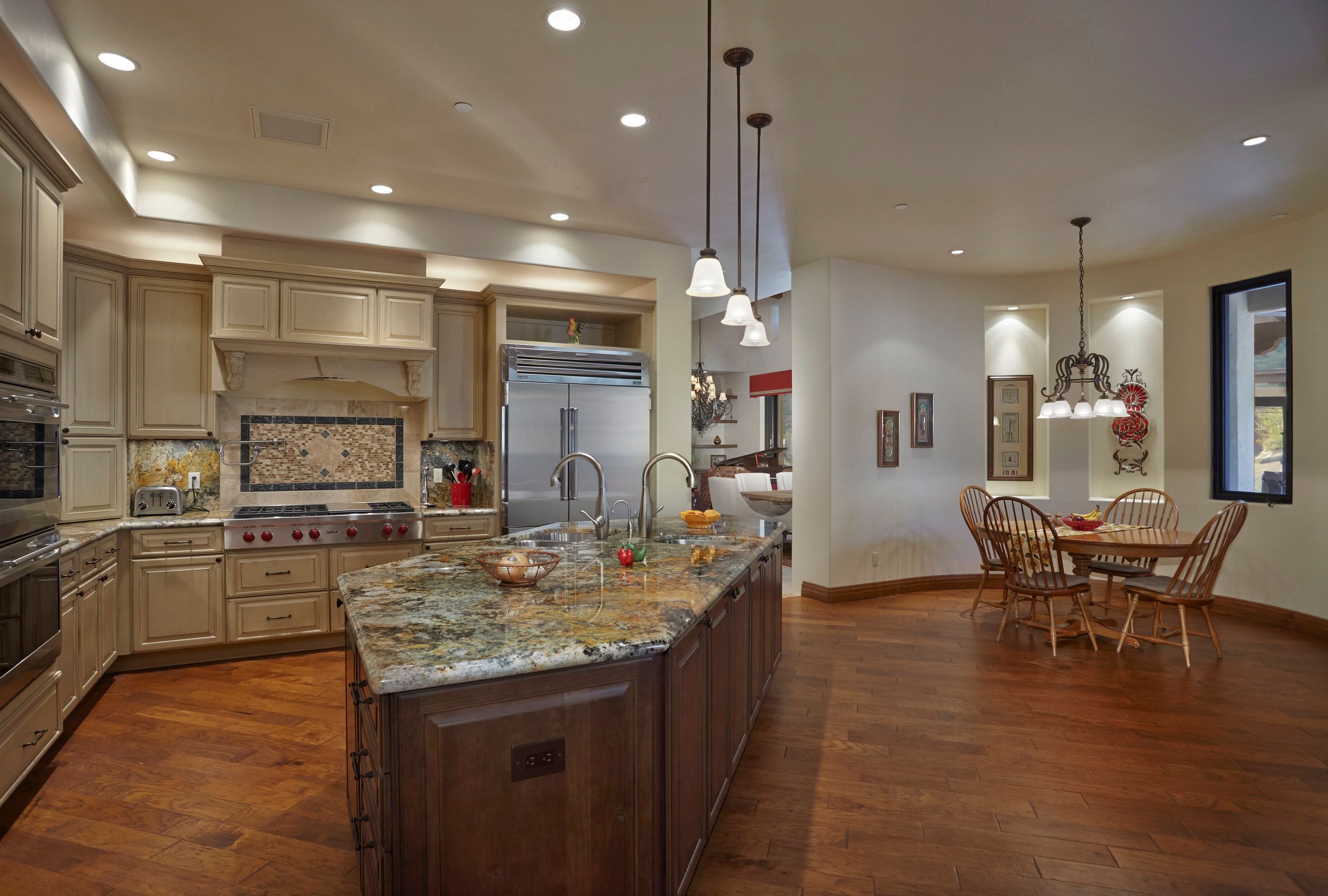 Kitchen with glazed cabinetry, a professional range and breakfast area beyond