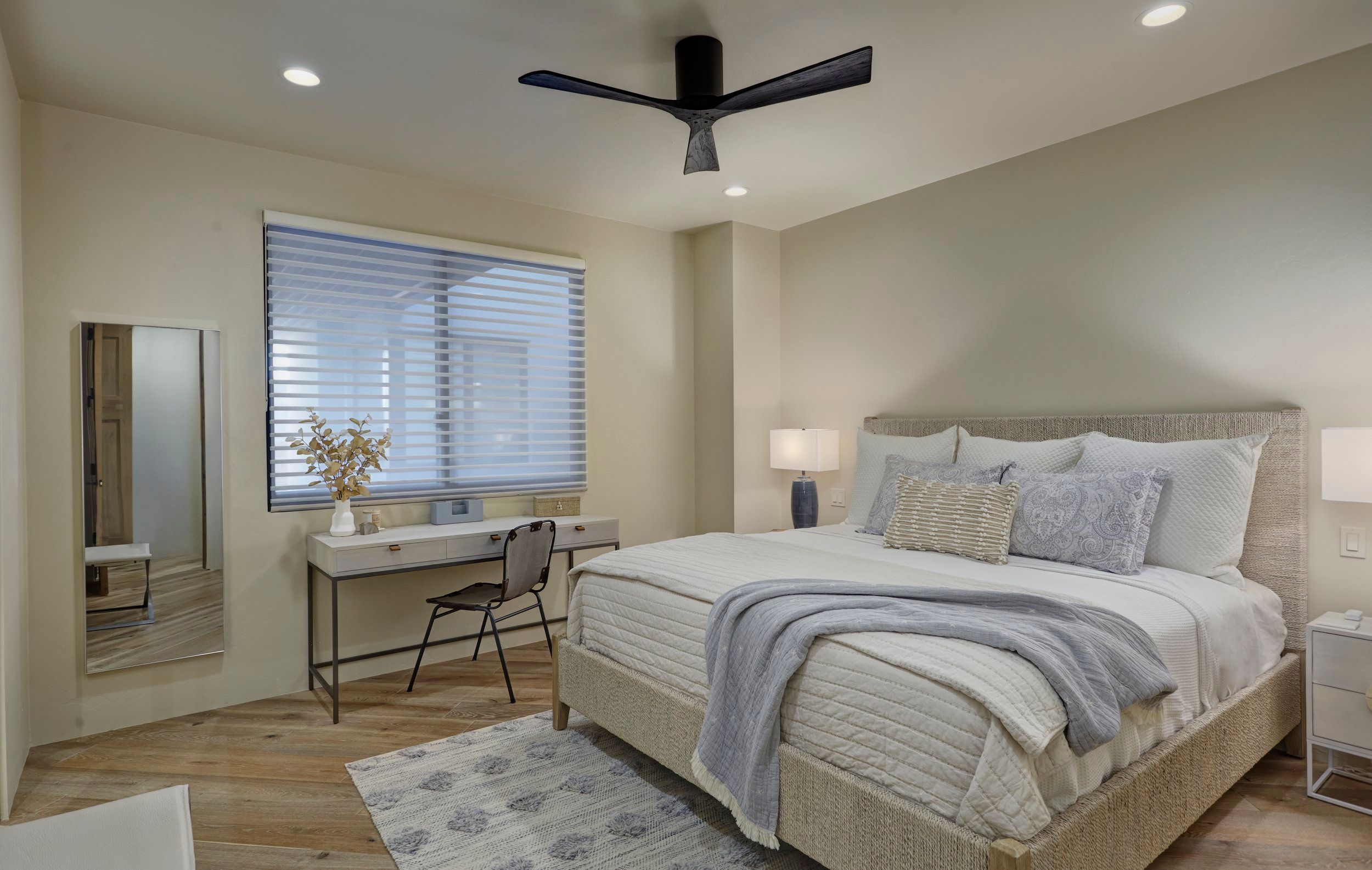 Guest bedroom with a ceiling fan, writing desk and shuttered window