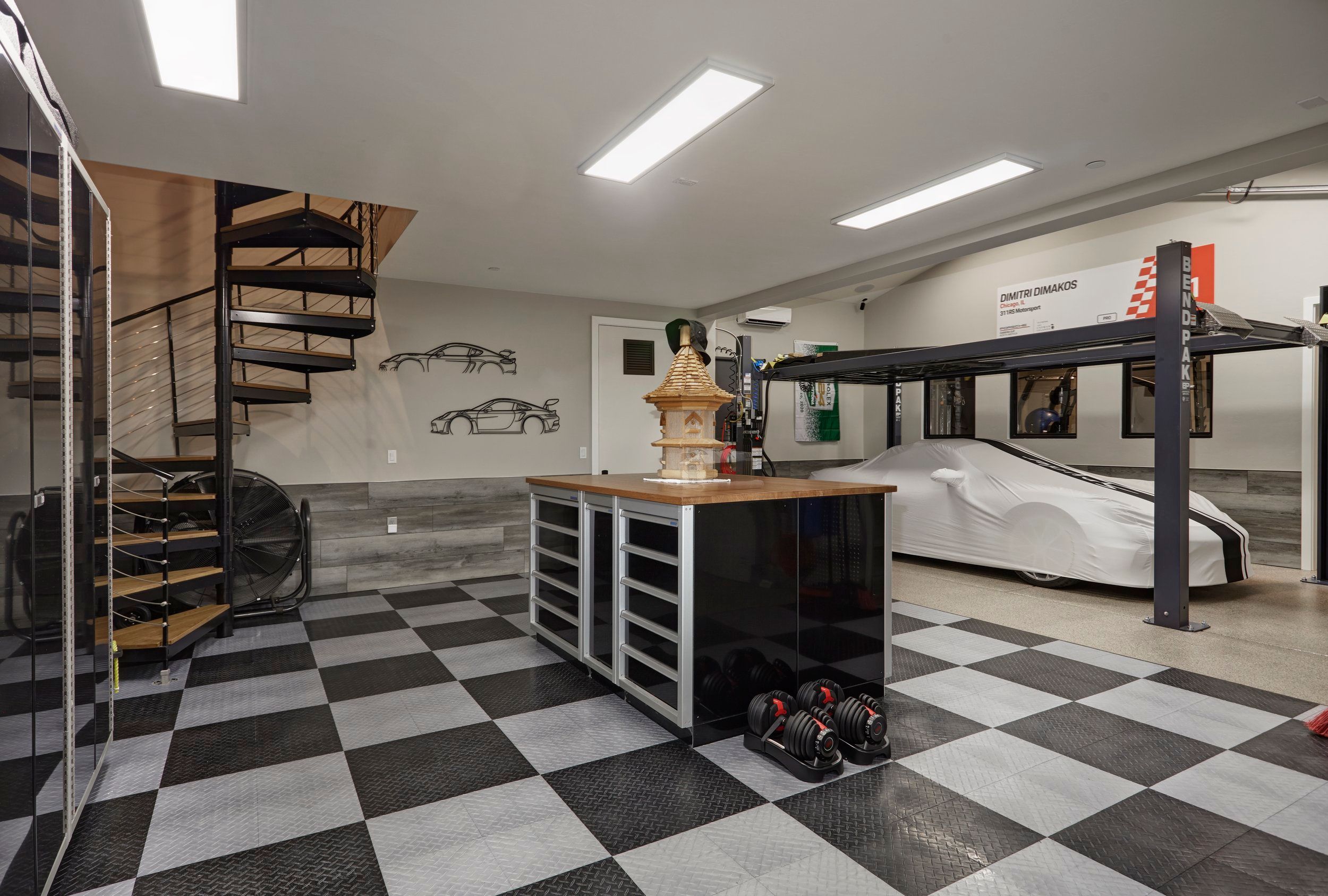 Garage and car showroom with a checkerboard floor, spiral staircase and vehicle lift