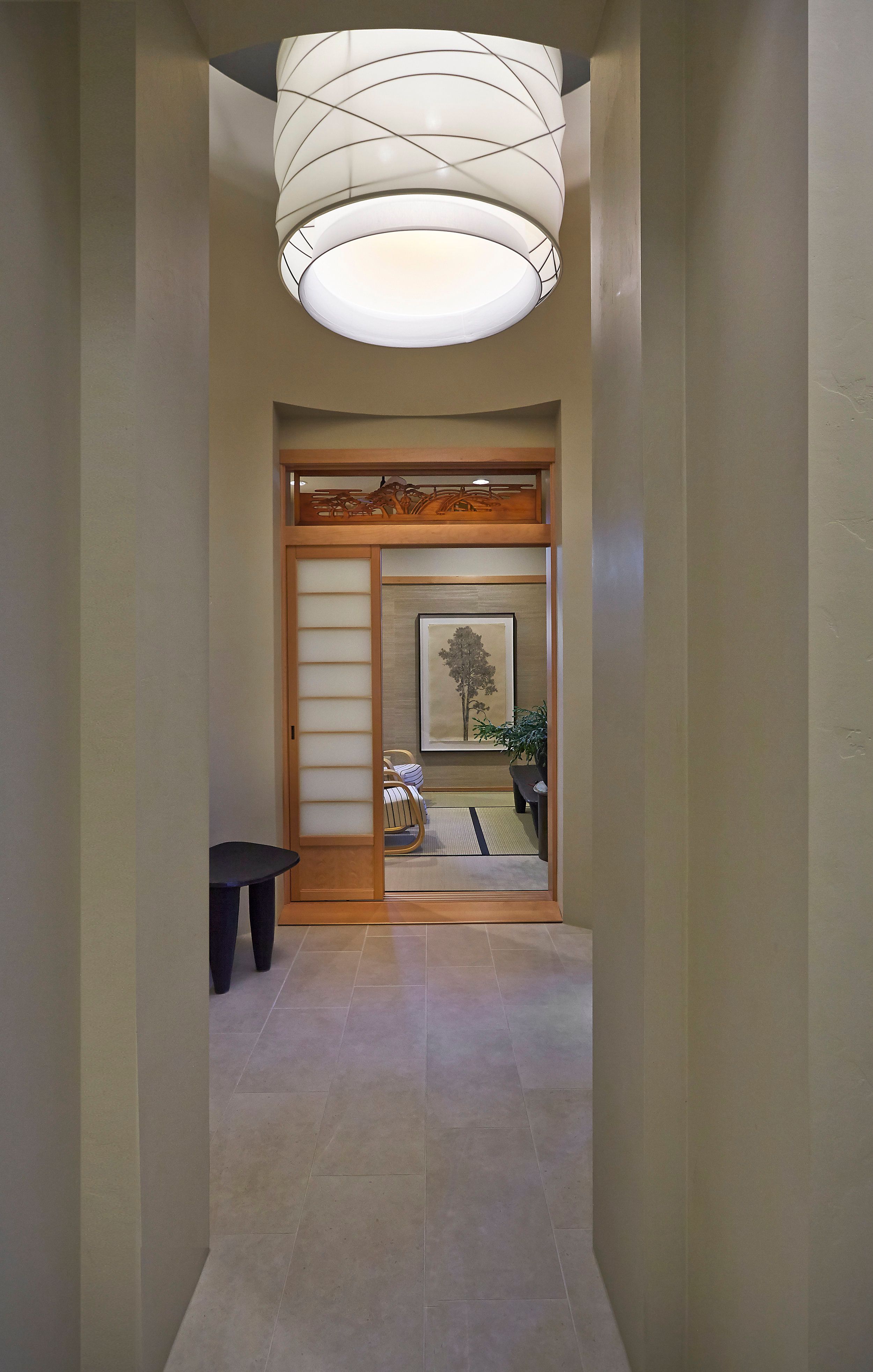 Curved hallway with a drum pendant light leading to a shoji-screened room