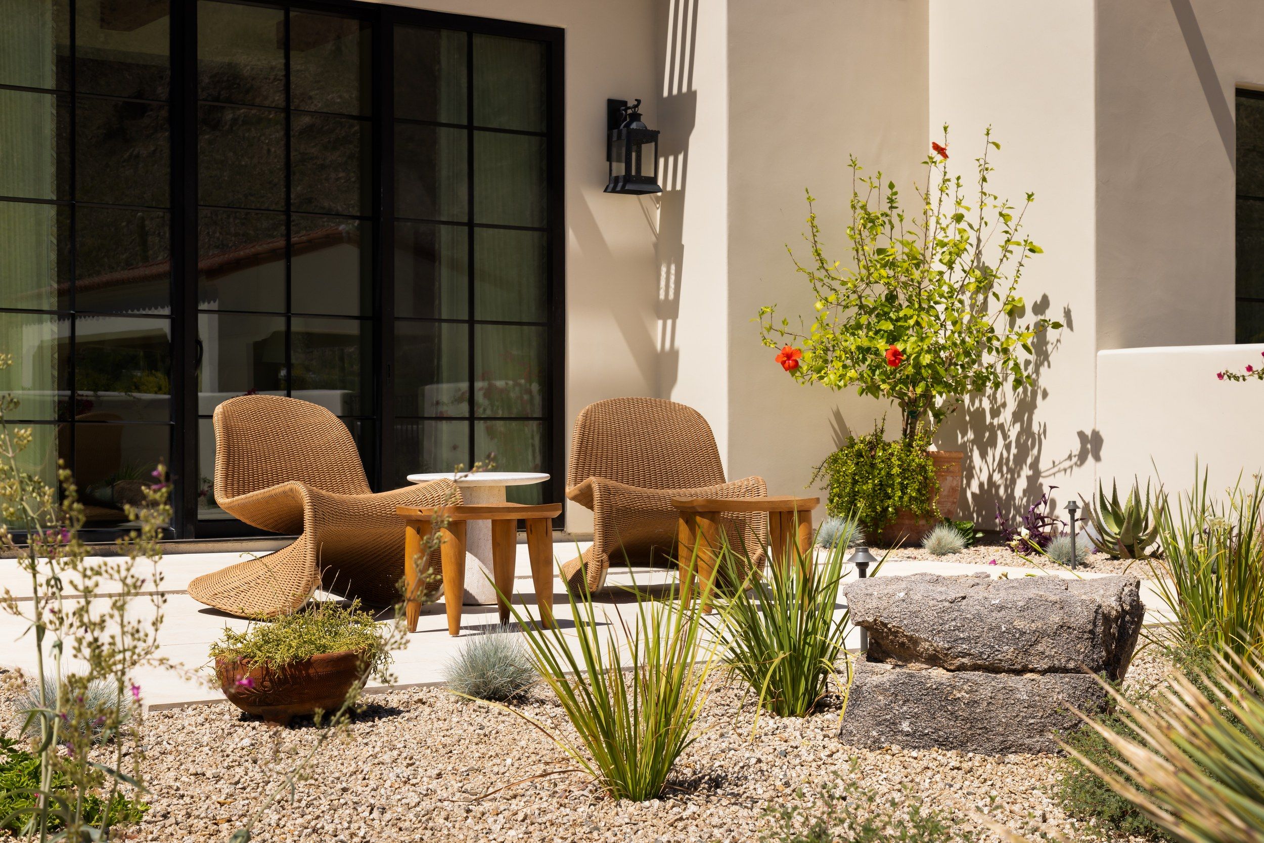 Side patio with woven armchairs, desert planting and steel doors