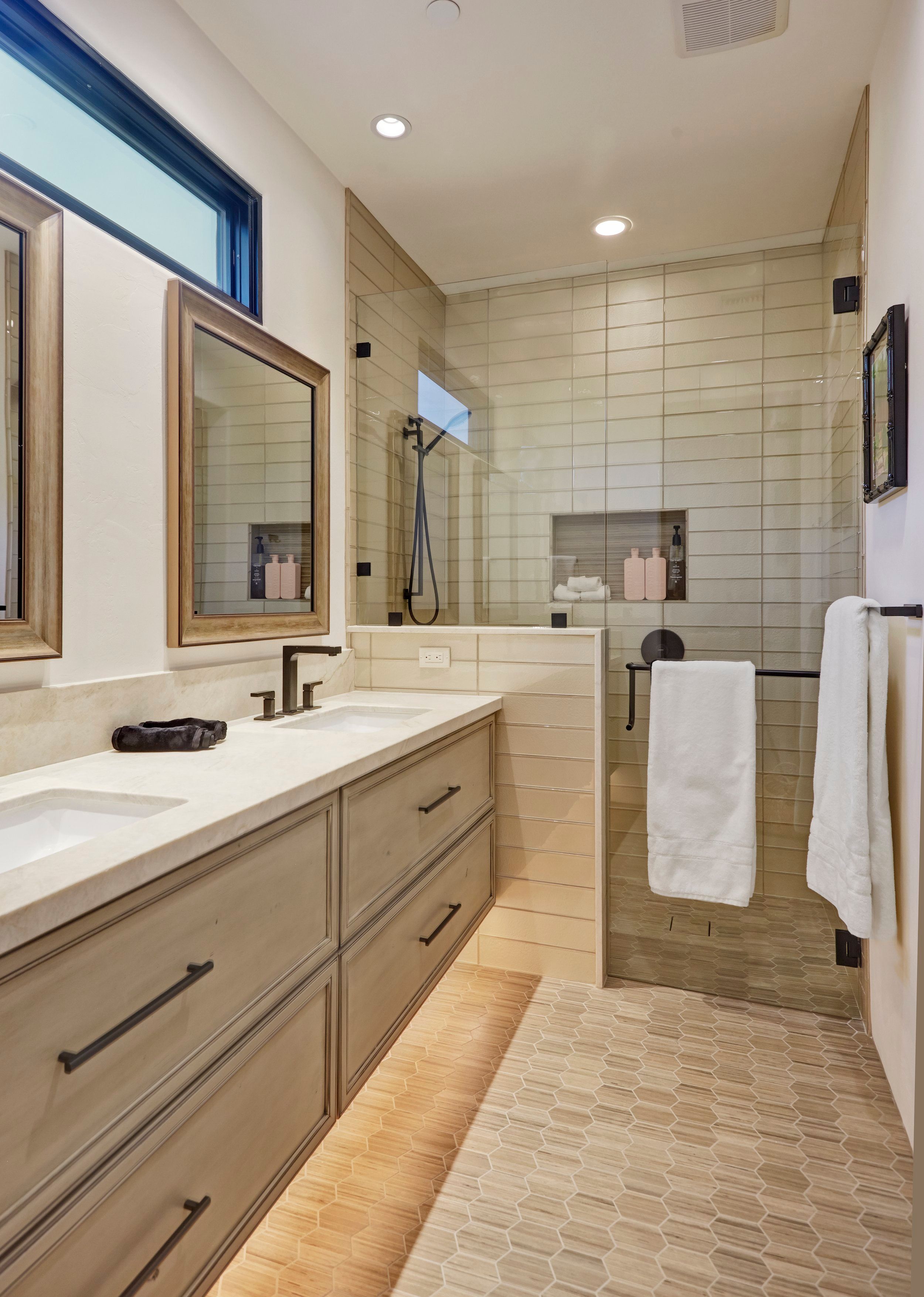 Primary bathroom with twin vanities, framed mirrors and a walk-in tiled shower