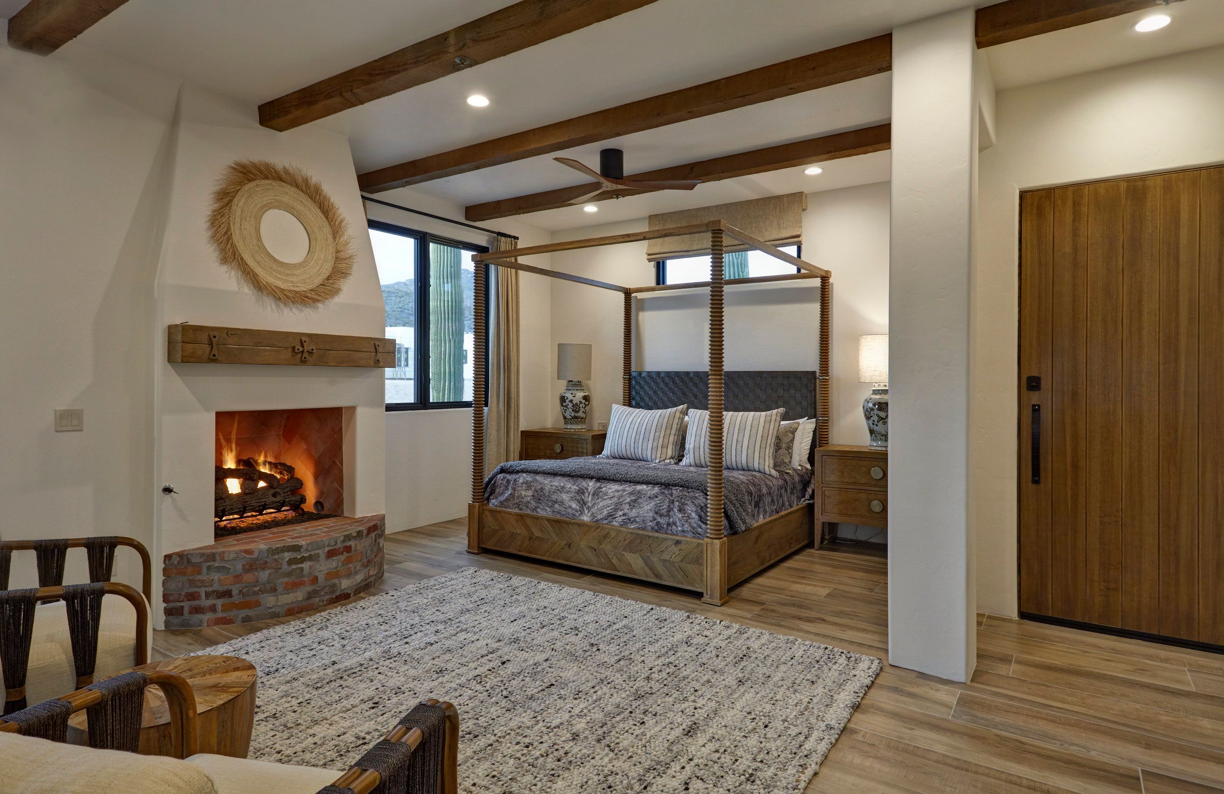 Bedroom with a corner brick fireplace, exposed beams and a four-poster bed