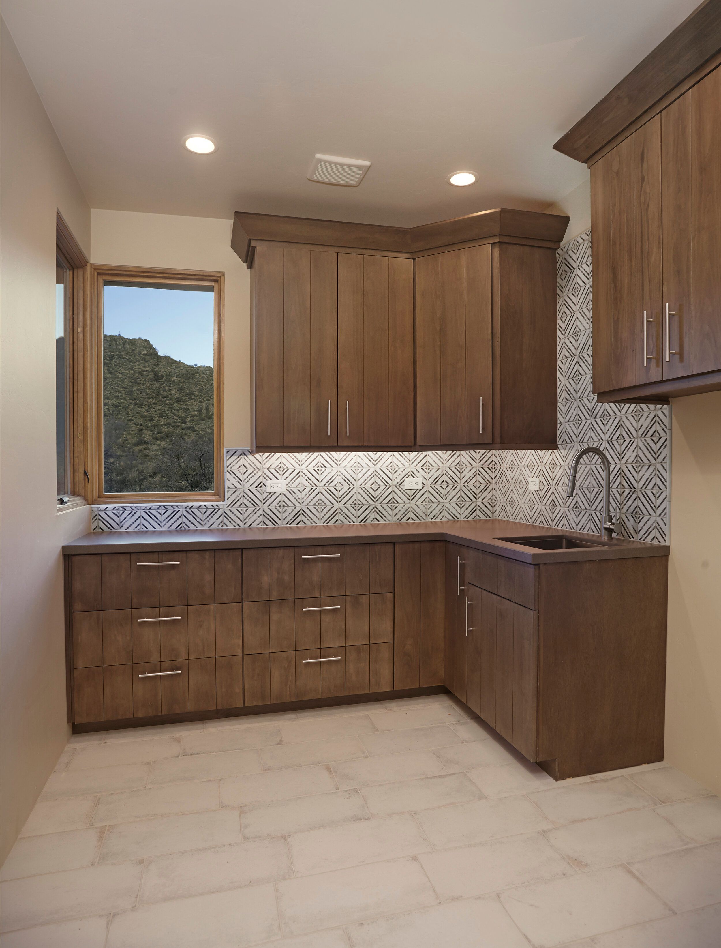 Laundry room with dark cabinetry, a patterned tile backsplash and utility sink
