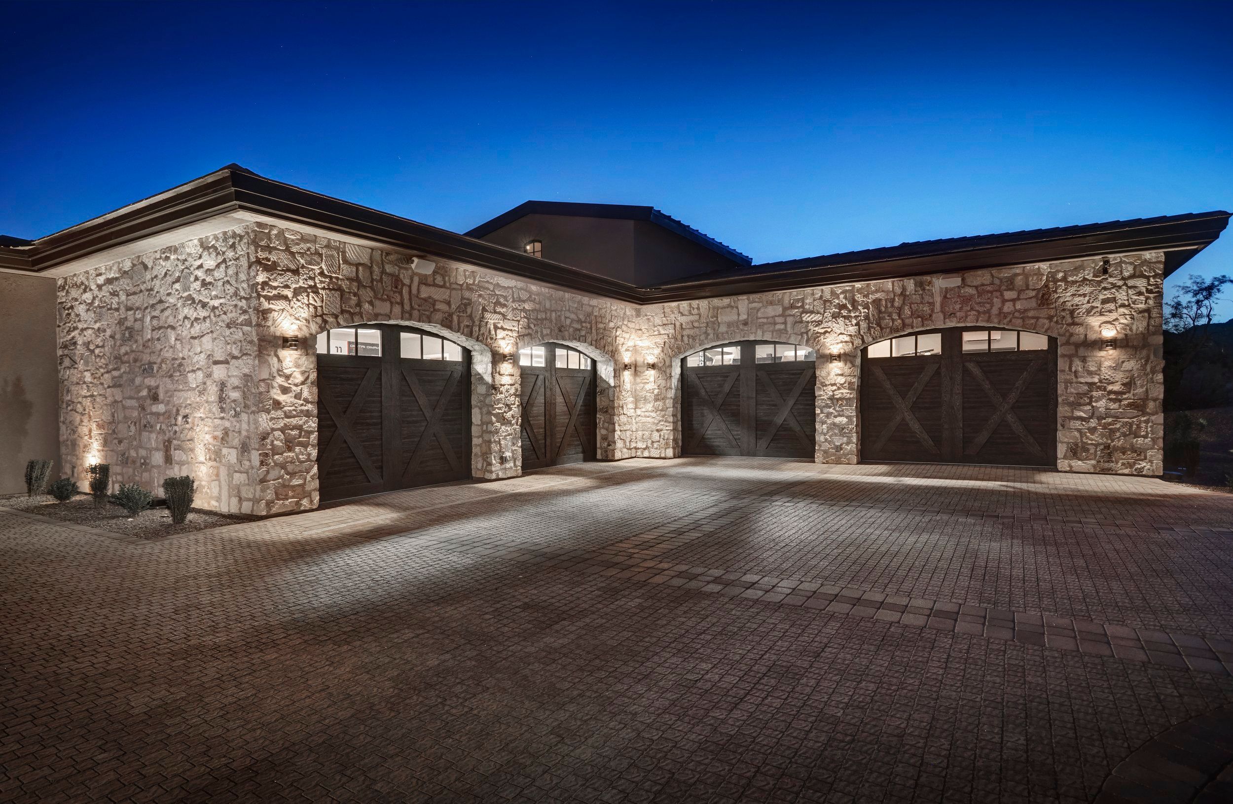 Three-bay stone garage with arched doors lit at night