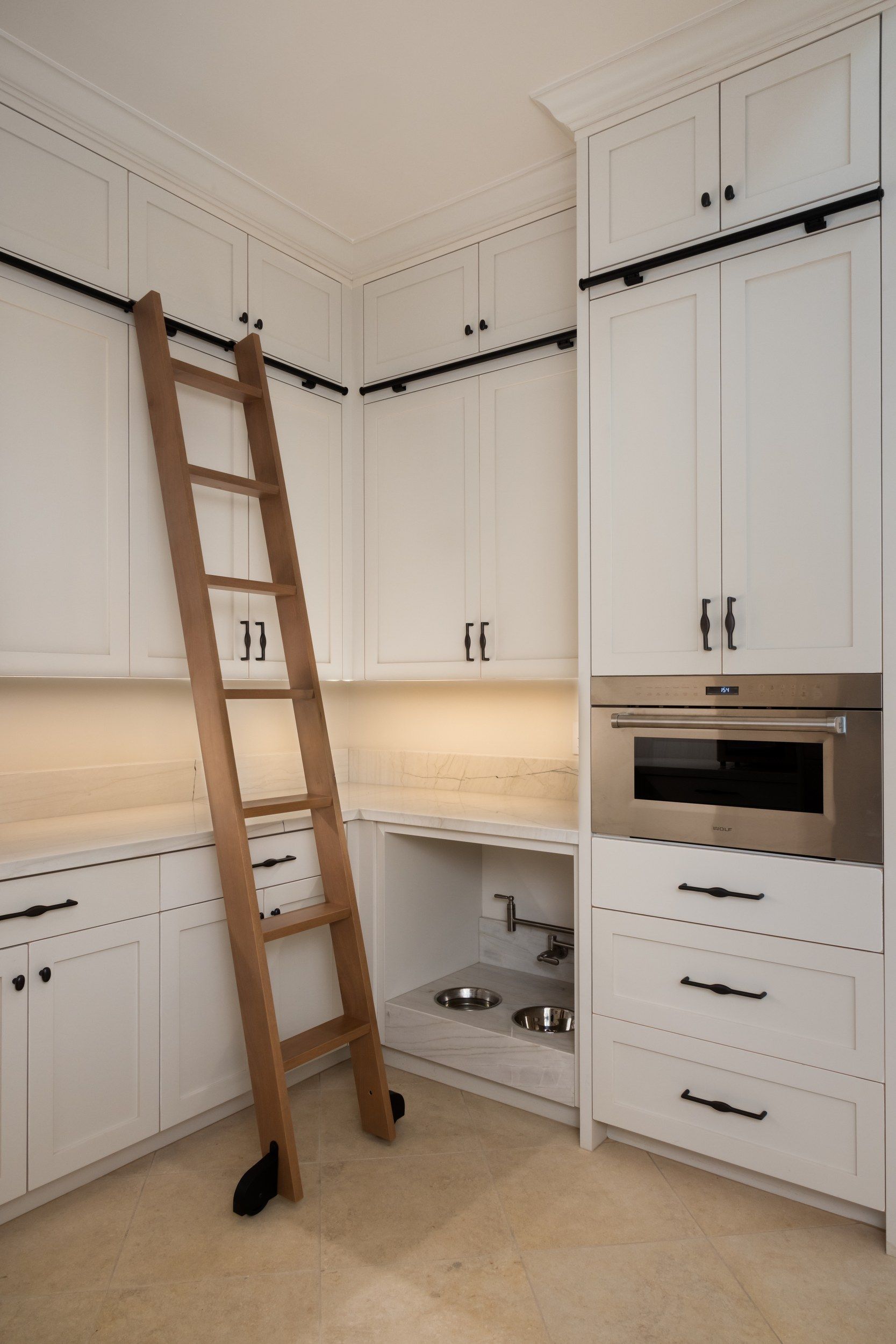 Pantry with a rolling library ladder and full-height cabinetry
